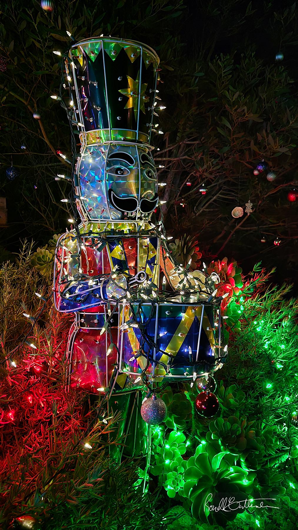 nighttime image of life-size nutcracker soldier outlined in Christmas lights