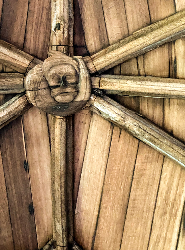 A vaulting boss from the cloister at Lincoln Cathedral, decorated with a droll face.