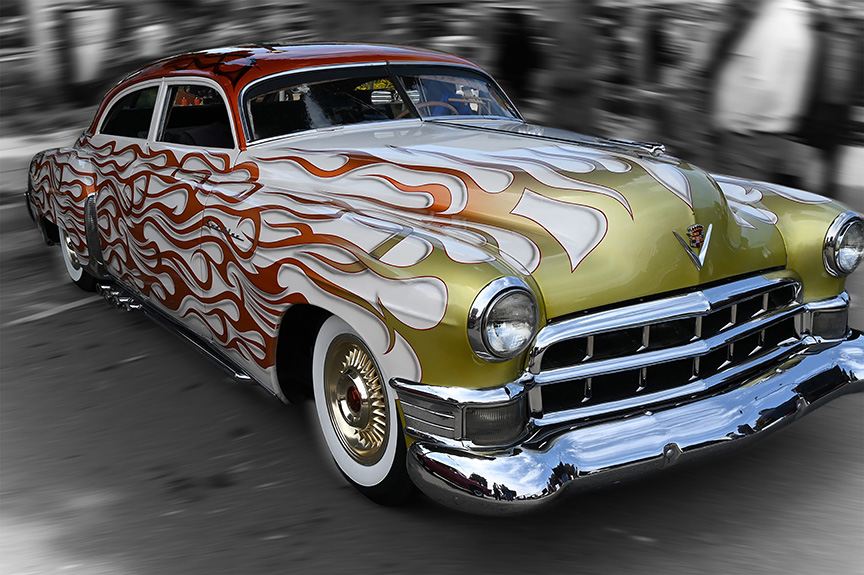 Photo of a boldly painted and restored 1950s Cadillac automobile, with a blurred, monochrome background.