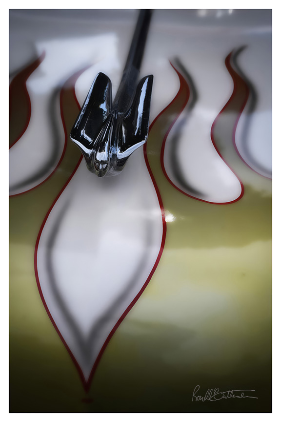 Hood ornament in the shape of a figure with wings, against a flame-painted hood.